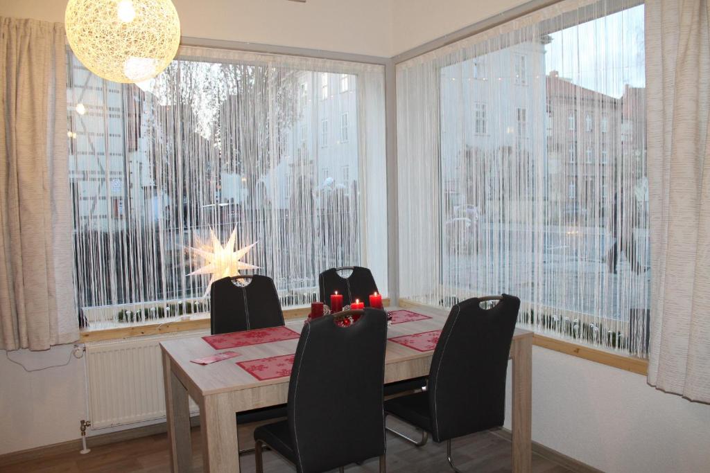 uma sala de jantar com mesa e cadeiras e janelas grandes em Ferien im Laden em Quedlinburg