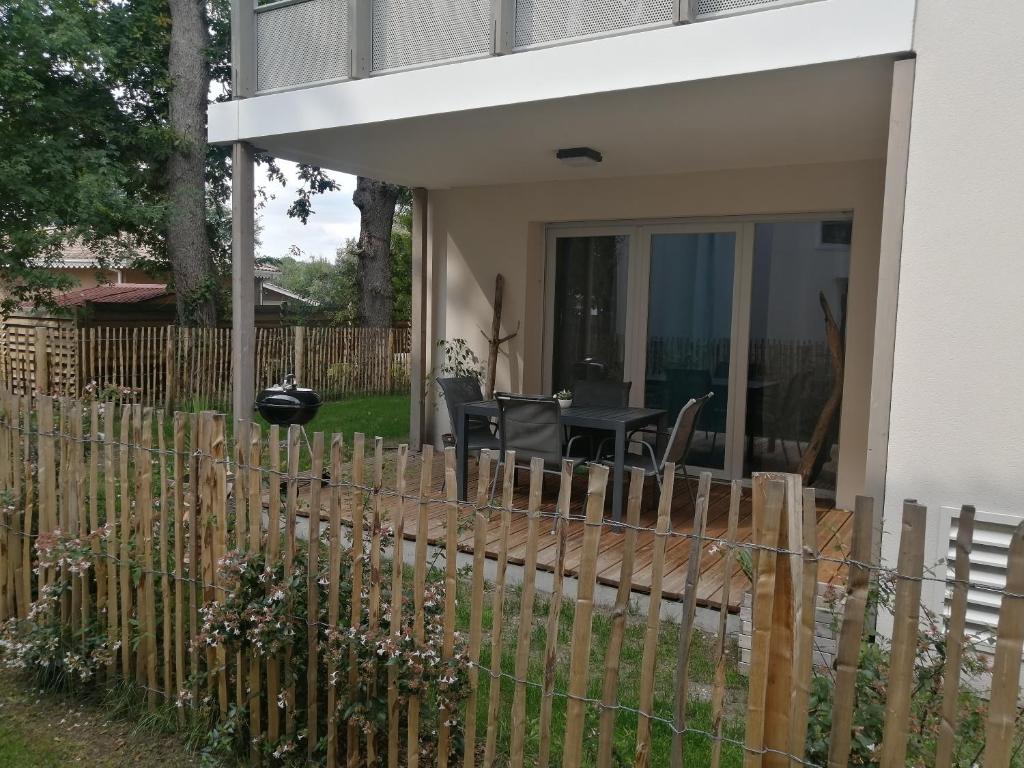 une clôture en bois devant une maison dans l'établissement Appartement calme avec jardin dans résidence neuve, à Carcans