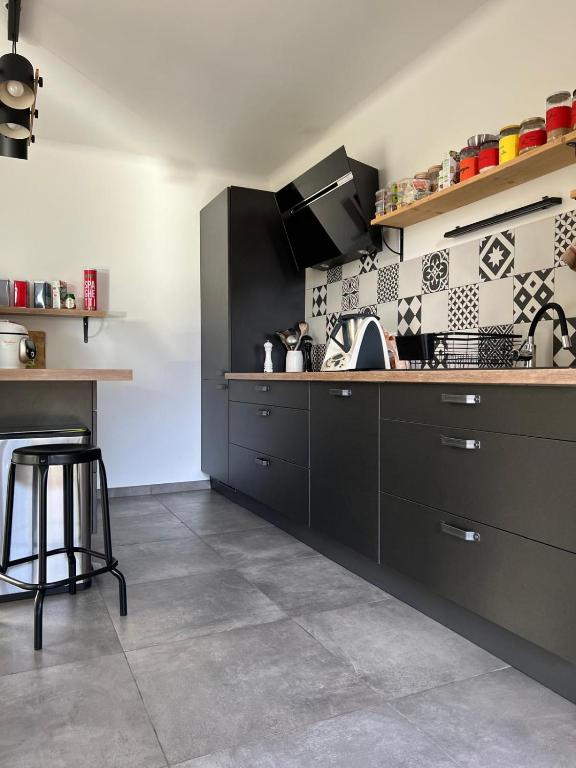 Il comprend une cuisine avec des placards noirs et du carrelage. dans l'établissement Villa Saint Martin, à Malemort-du-Comtat