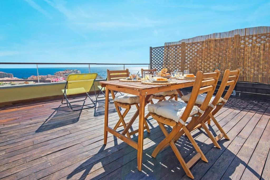 - une table et des chaises en bois sur une terrasse donnant sur l'océan dans l'établissement Maison savorani, à Cap d'Ail