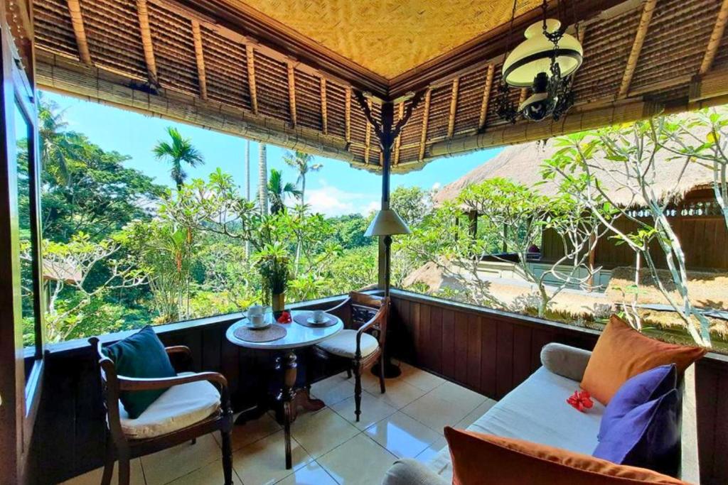 a room with a balcony with a table and chairs at Kavita 1 BR Grand Deluxe Valley View ZN236 in Ubud