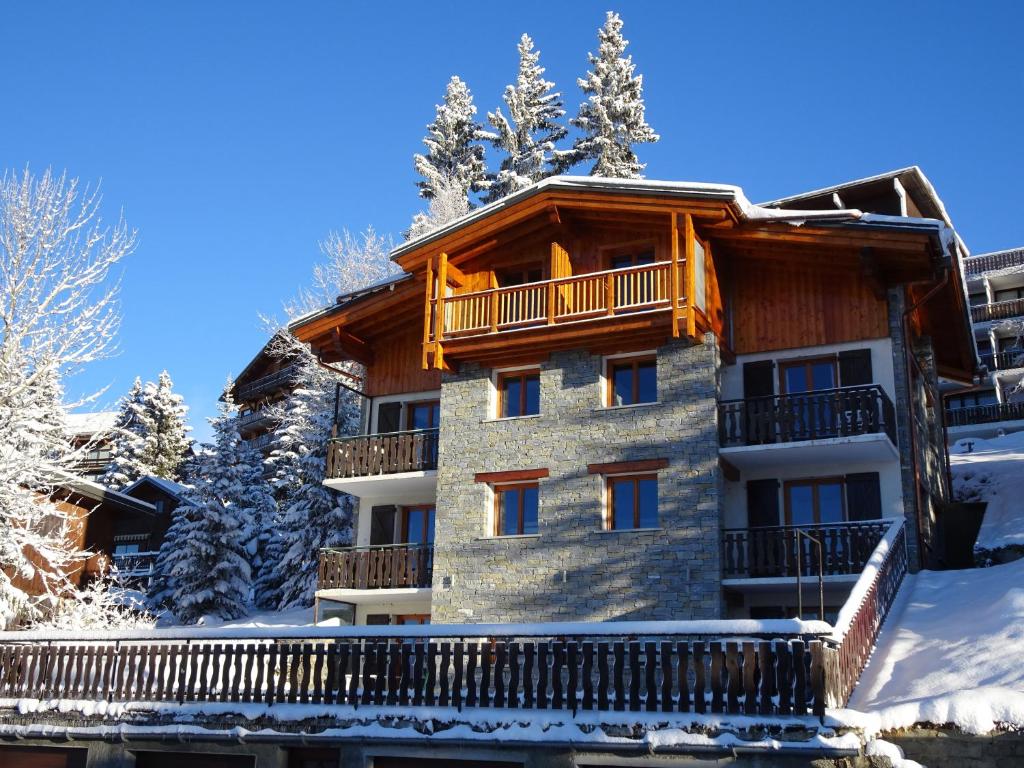 un immeuble avec un balcon sous la neige dans l'établissement Appartement dans un chalet typique de montagne à La Rosière, à Montvalezan
