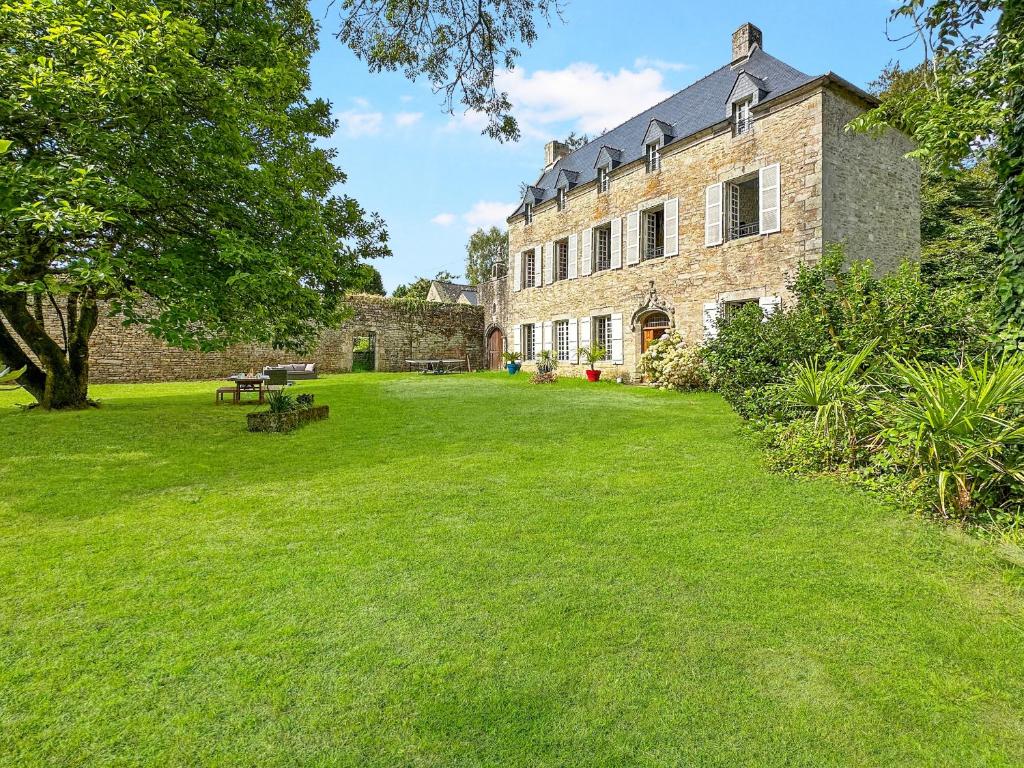 - un grand bâtiment en briques avec une pelouse dans l'établissement Keriner manoir 10 pieces avec parc arbore, à Pluguffan