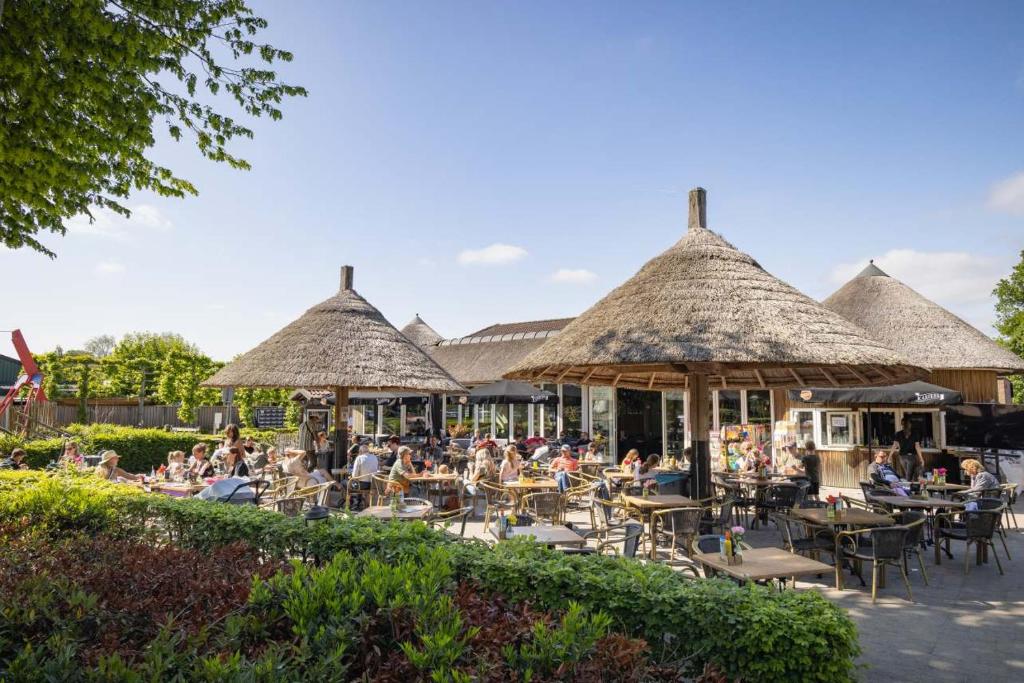 een groep mensen aan tafels met rieten paraplu's bij Camping Marvilla Parks Kaatsheuvel in Kaatsheuvel