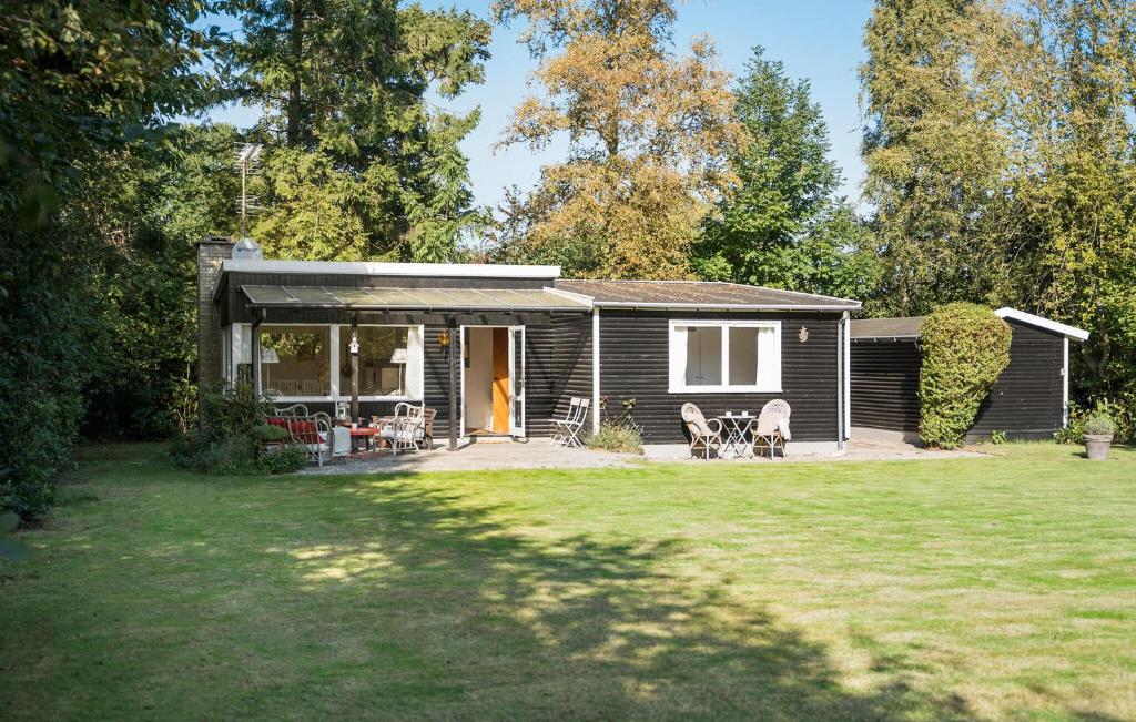 a small cabin with a porch and chairs in a yard at 2 Bedroom Lovely Home In Dronningmølle in Dronningmølle