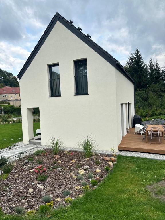 a white house with a deck and a patio at MINIMAL. Dom całoroczny w górach in Duszniki Zdrój