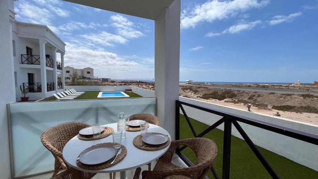 a table and chairs on a balcony with a view of the beach at Casa Fin del Mundo El Cotillo in Cotillo