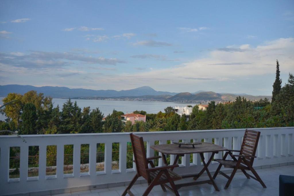 a table and chairs on a balcony with a view of the water at Caecilia & Lawrence Villa in Chalkida