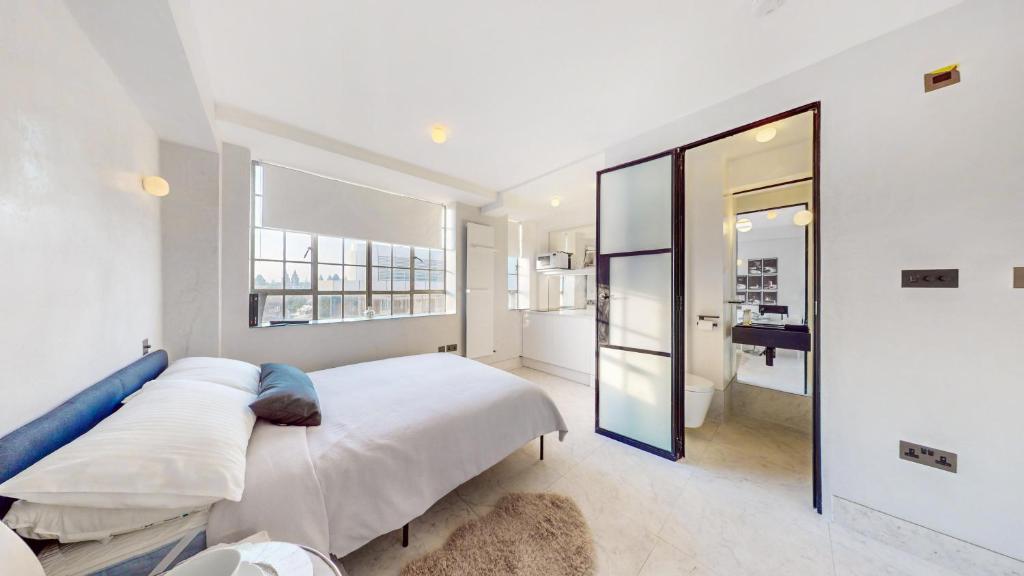 a white bedroom with a large bed and a mirror at Sloane Cloisters 767 in London