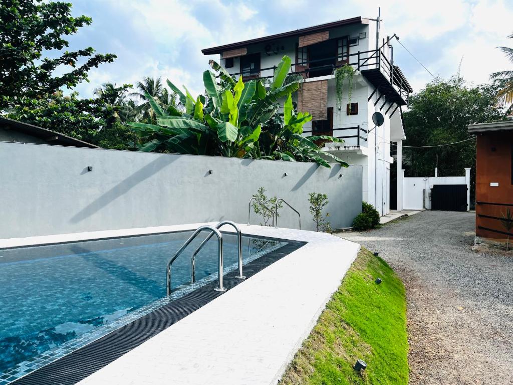 a swimming pool in front of a house at Hotel Vish Ceylon in Talawatugoda