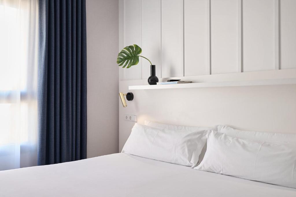 una camera da letto con un letto con lenzuola bianche e una pianta di Ramirez Flats Valencia a Valencia