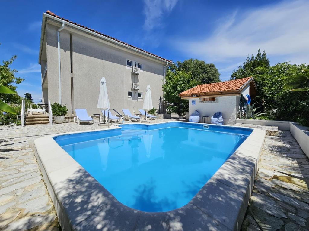 a swimming pool in front of a house at Apartments Mirko in Malinska