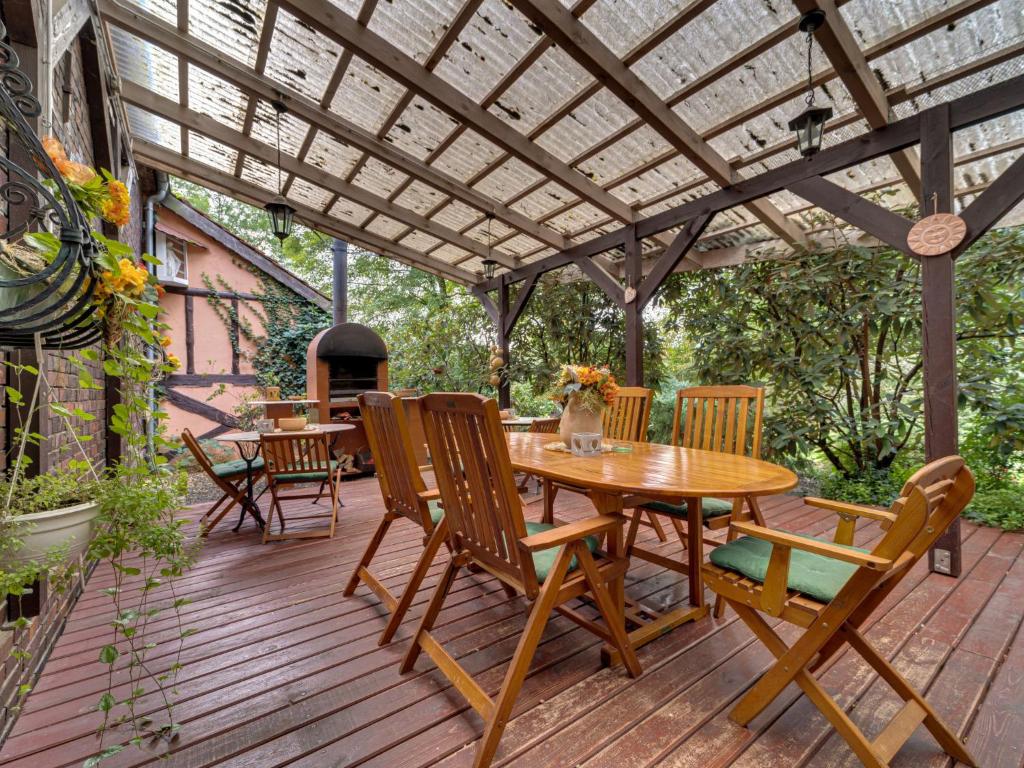 a wooden deck with a pergola and tables and chairs at Holiday Home Gościniec Pod Dwoma Sercami by Interhome in Tuplice