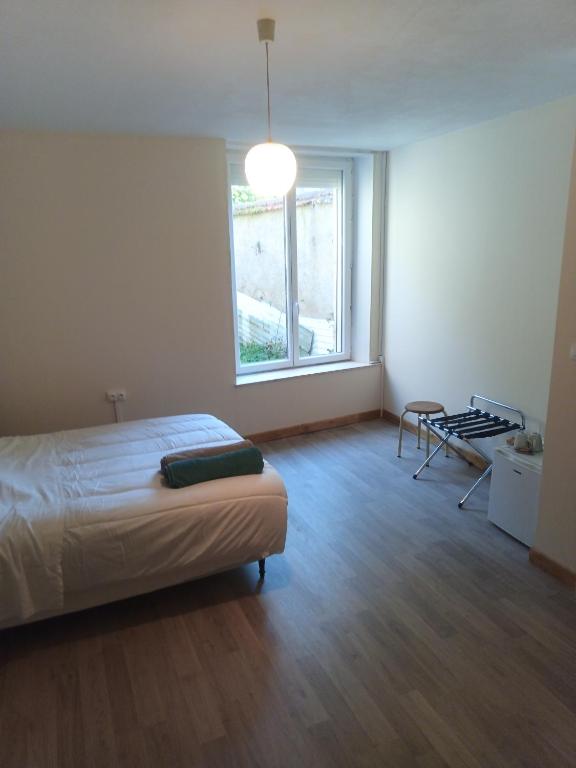 une chambre avec un lit et une grande fenêtre dans l'établissement Le Senarmont, à Saint-Mihiel