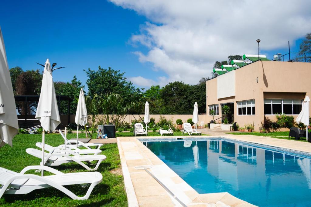a swimming pool with white chairs and umbrellas at Hotel del Rio - La Cruz Corrientes in La Cruz