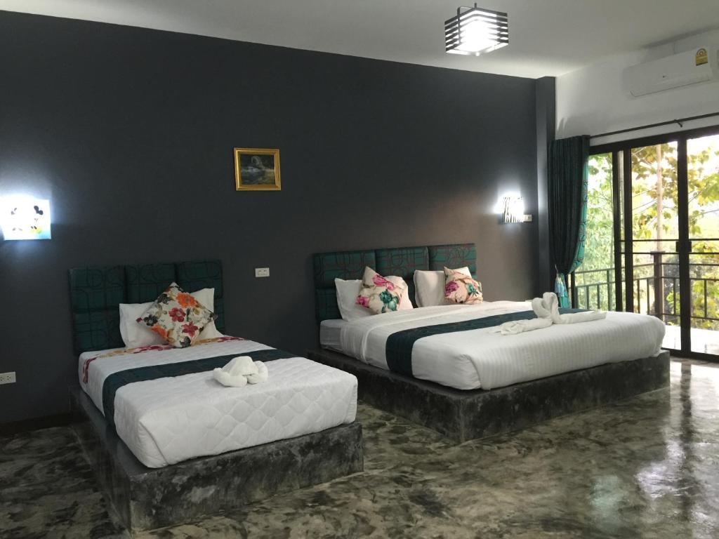 2 camas en una habitación con paredes negras en Baan Rai Phufah Resort Chiangrai, en Ban Pa Ruak