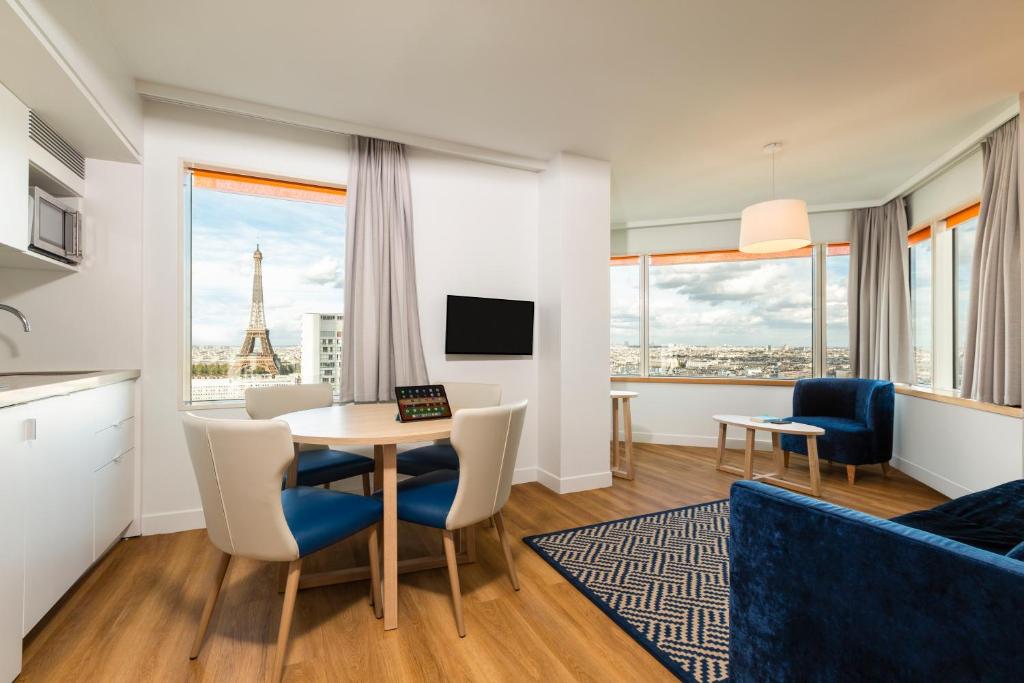 a living room with a table and chairs and the eiffel tower at Aparthotel Adagio Paris Centre Tour Eiffel in Paris