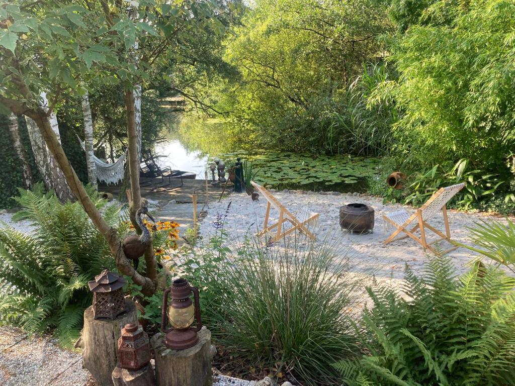 Un jardín con sillas y árboles y un río. en Het Zalige Buitenleven, en Lanaken
