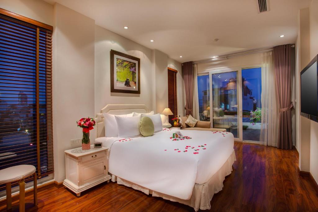 Un dormitorio con una gran cama blanca con flores. en Mercury Central Hotel Hanoi, en Hanói