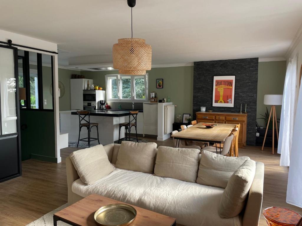 a living room with a white couch and a kitchen at Maison de famille 5 ch idéale pour des réunions de familles in Sainte-Luce-sur-Loire