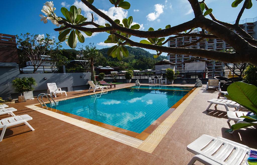 a swimming pool with white chairs and a building at Platinum Hotel and Apartments in Patong Beach