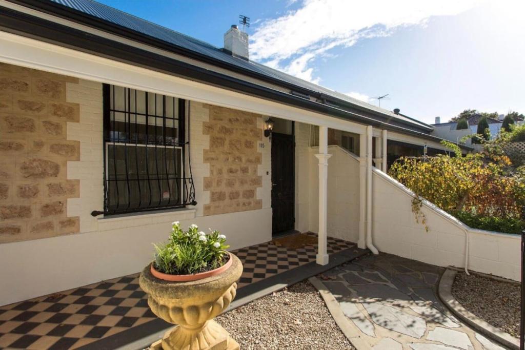 a house with a flower pot on a checkered floor at North Adelaide Row Cottage Monte in North Adelaide