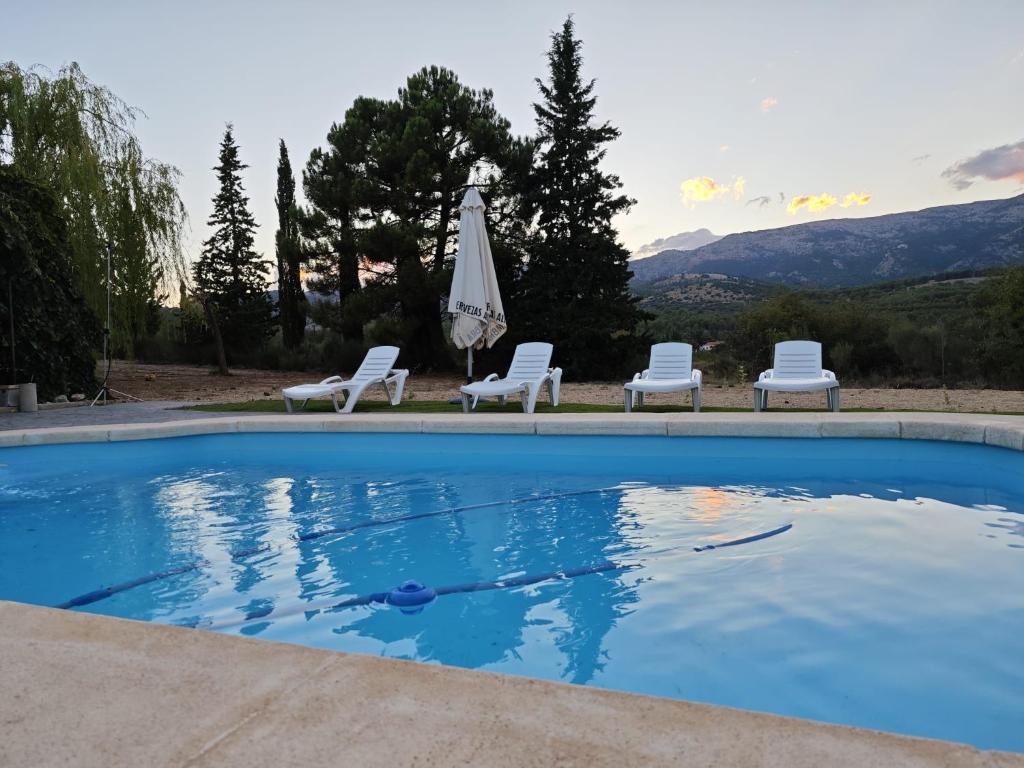 a swimming pool with two chairs and an umbrella at Casa El Rincón del Guardal in Huéscar