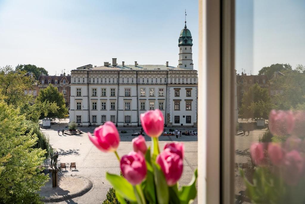 Una ventana con tulipanes rosas frente a un edificio. en Amazing apartament in the heart of Kazimierz, en Cracovia
