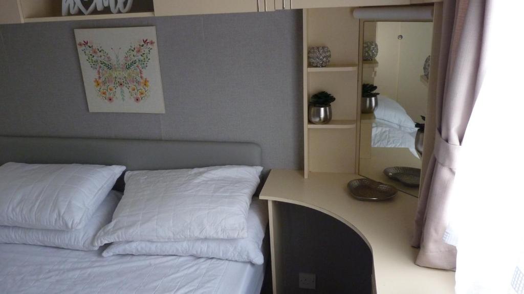 ein Schlafzimmer mit einem Bett und einem Schreibtisch mit Spiegel in der Unterkunft L&g FAMILY HOLIDAYS 6 BERTH CORAL BEACH LAURA FAMILYS ONLY AND LEAD PERSON MUST BE OVER 30 in Ingoldmells