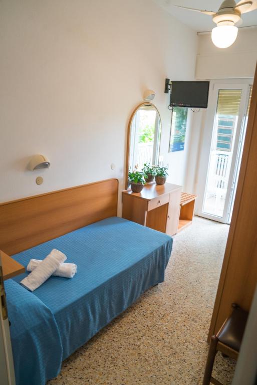sypialnia z niebieskim łóżkiem i lustrem w obiekcie Hotel Singapore w mieście Milano Marittima