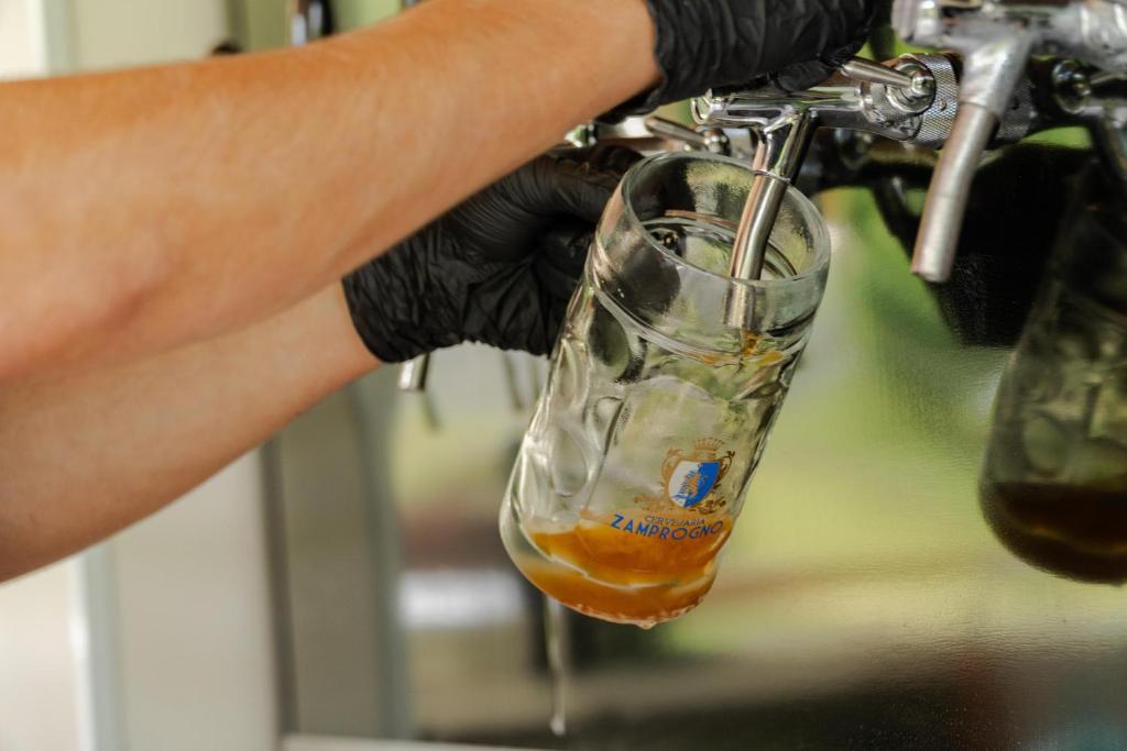 a person wearing gloves holding a drink in a glass at Villaggio Zamprogno in Santa Teresa