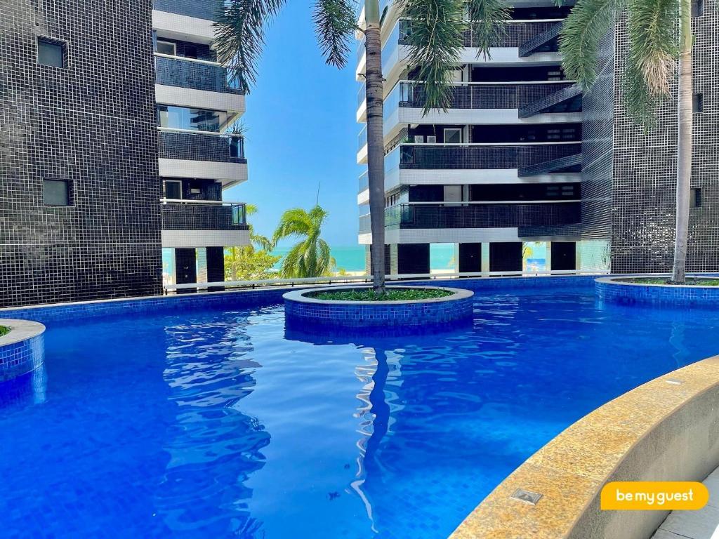 a swimming pool with a palm tree in front of a building at Landscape melhores apartamentos da Beira Mar in Fortaleza