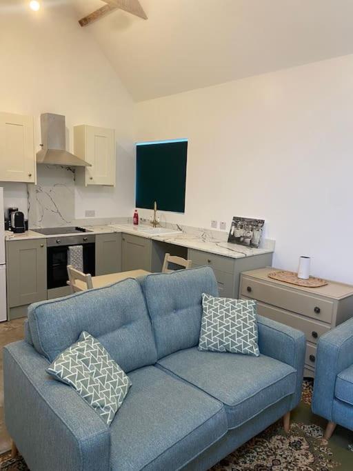 a living room with a blue couch and a kitchen at 2 bed cozy cottage in Wansford