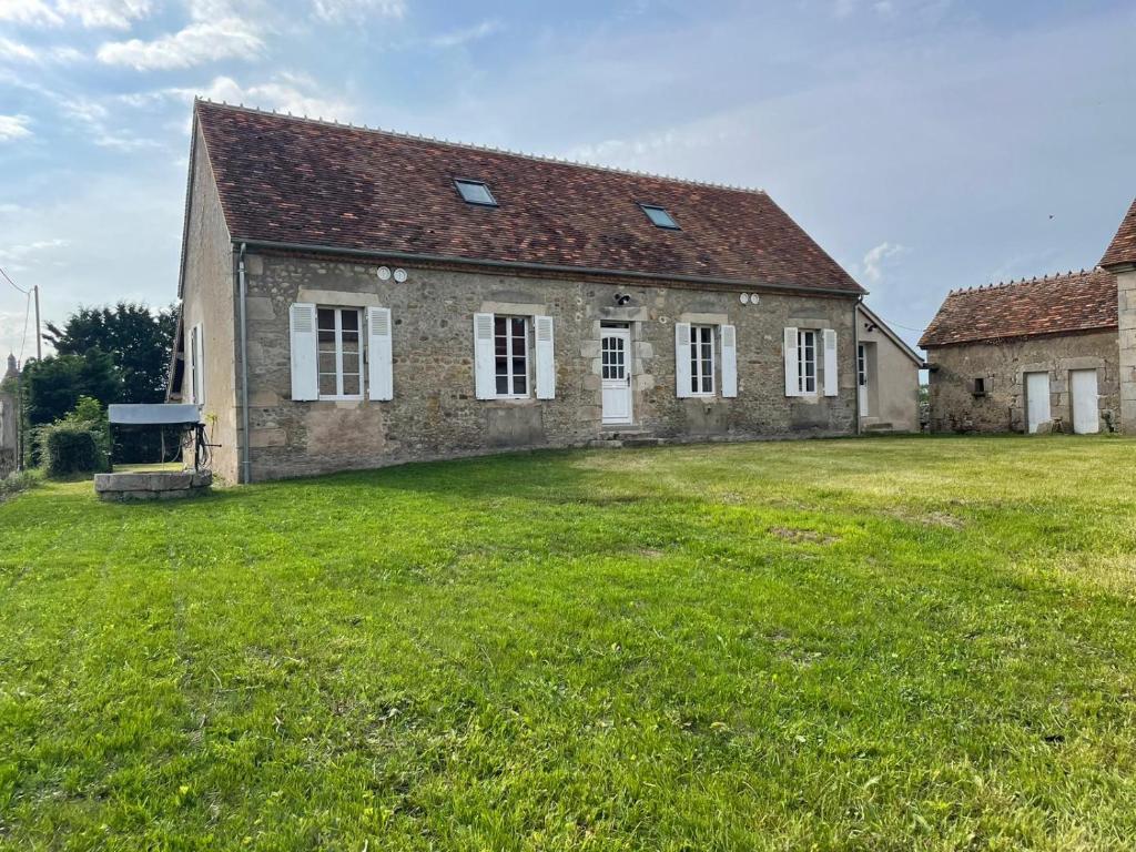une ancienne maison en briques avec une grande pelouse dans l'établissement Farmhouse of Château de La Motte-Feuilly, à La Motte-Feuilly