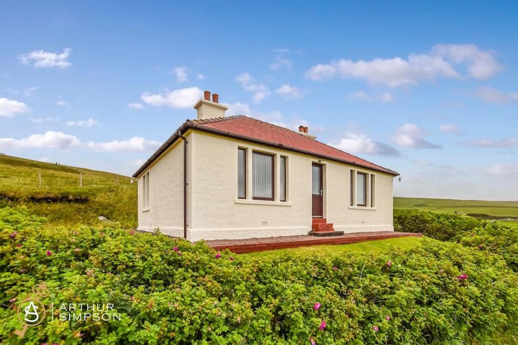 a small white house with a red roof in a field at Dunard - Charming three bedroom cottage in Bigton in Sandwick