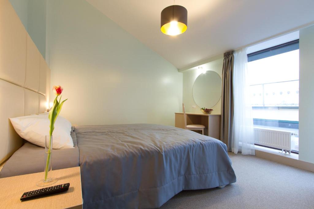 a bedroom with a bed and a vase with a flower on a table at Mini Hotel Nevskaya Panorama in Saint Petersburg