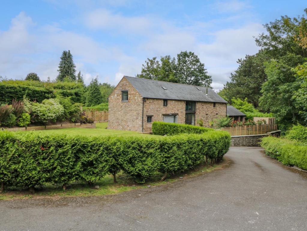 a stone house with a hedge in front of a driveway at The Ivy Barn in Abergavenny