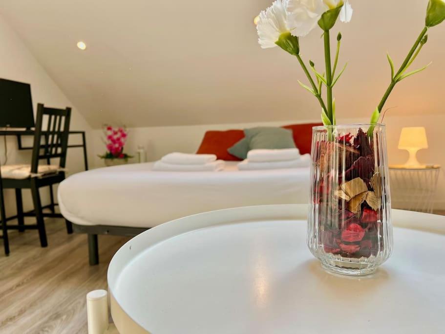 un vase avec des fleurs sur une table dans une pièce dans l'établissement Chez Léon - Calme & Lumière, à Reims