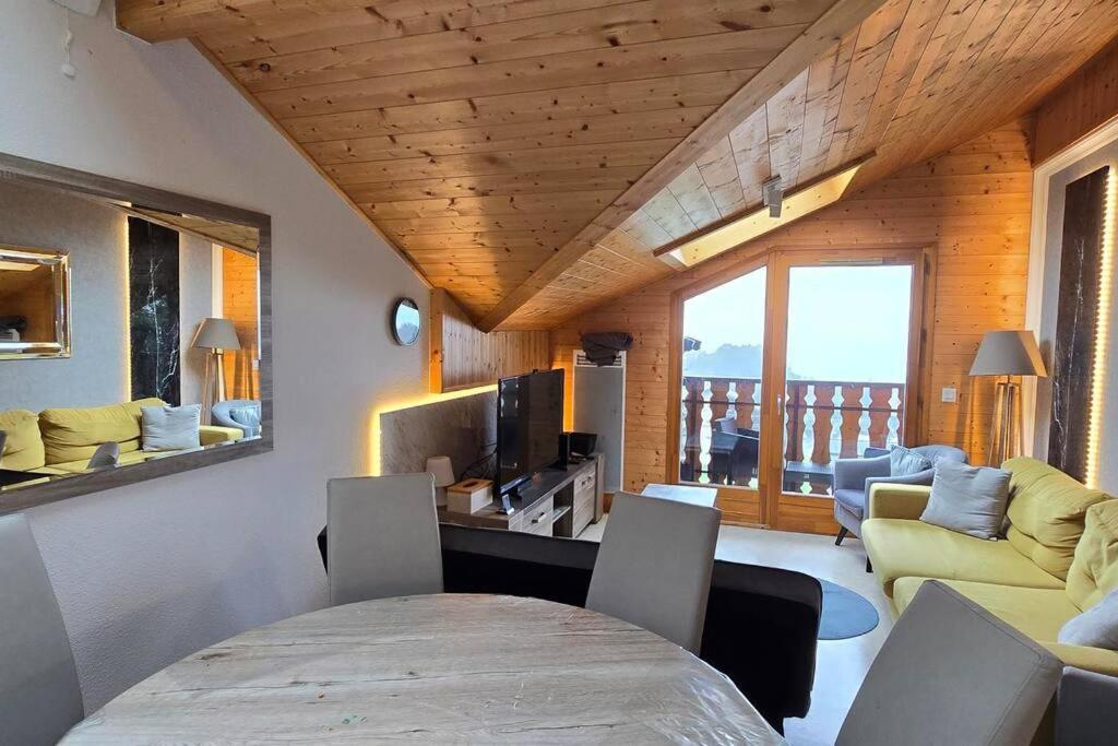 un salon avec un canapé et une table avec des chaises dans l'établissement Les Spatules, à Thollon-les-Mémises