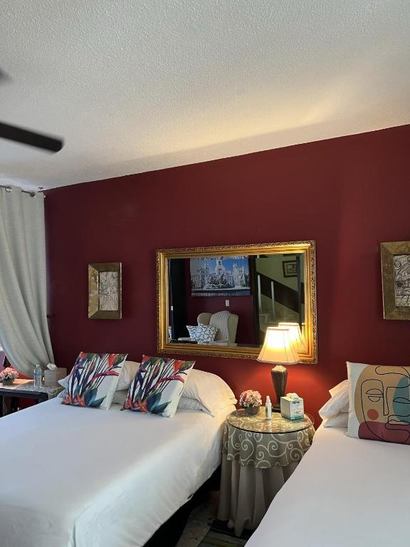 a hotel room with two beds and a mirror at Dickinson Guest House, Guadalajara Expo in Guadalajara