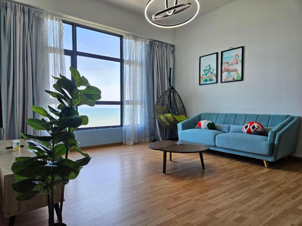 a living room with a blue couch and a large window at House Of 99 in Kuantan