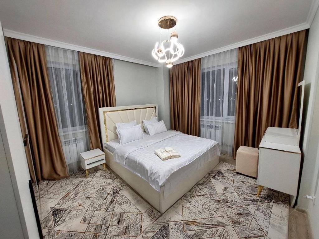 una camera da letto con un letto e un lampadario di Lux apartments in Turkistan a Türkistan