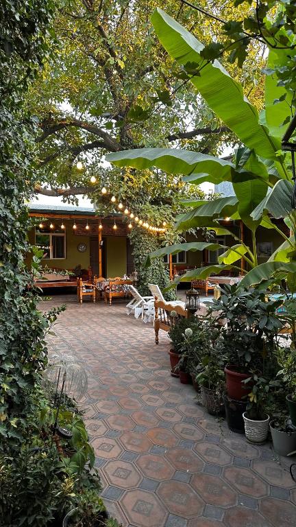 a patio with tables and chairs and trees and plants at Green Yard boutique guesthouse in Tashkent