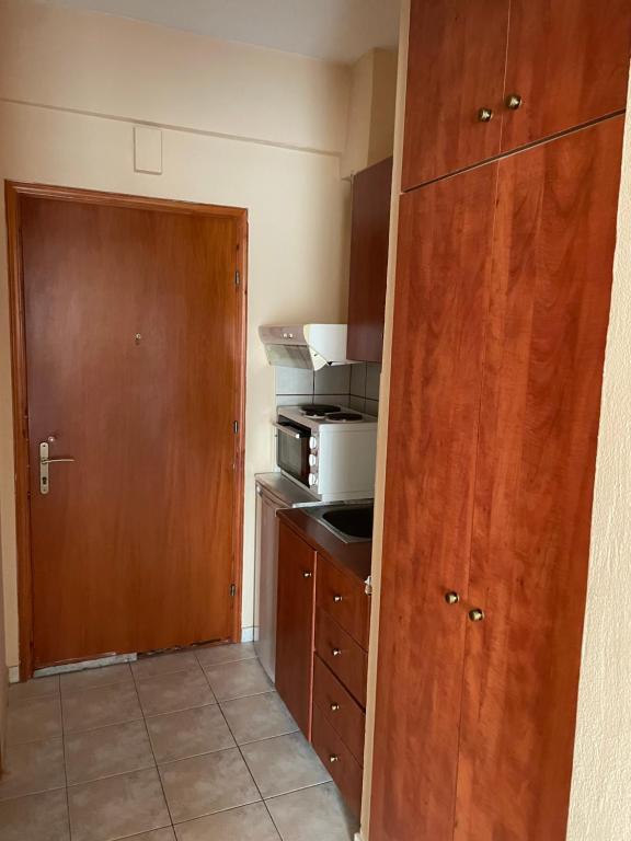 a small kitchen with a wooden door and a microwave at Λιέγη Orestiada apartment no 2 in Orestiada