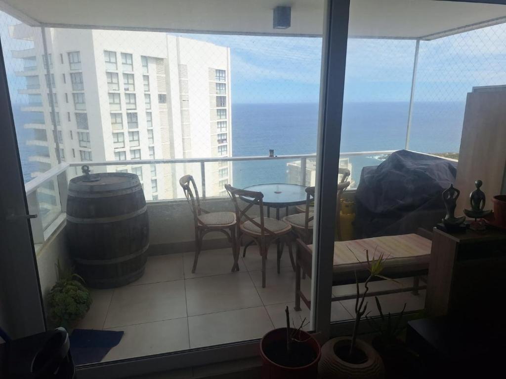 een balkon met een tafel en stoelen en de oceaan bij Dpto 2 piezas 2 baños al lado de las dunas de Concon in Viña del Mar