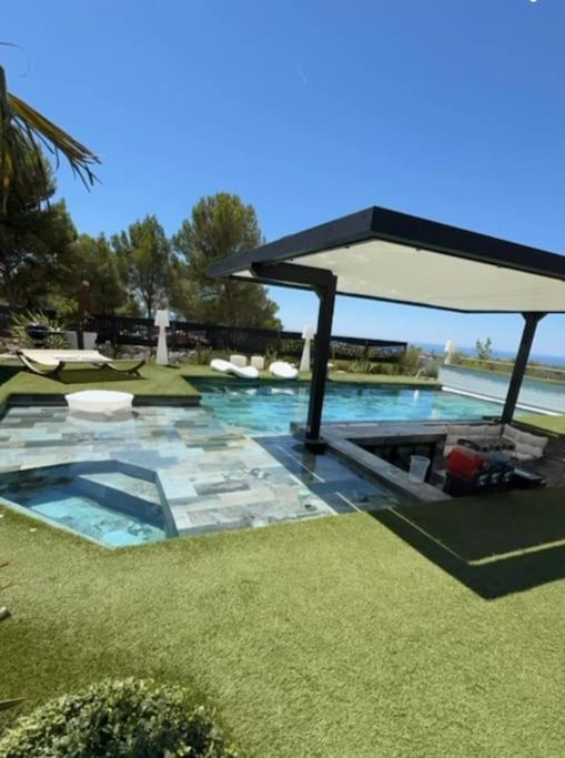 - une piscine avec un grand parasol et un peu d'herbe dans l'établissement Fabuleuse villa Marseille -7 chambres -14 pers avec grande piscine 2 jacuzzis, à Marseille
