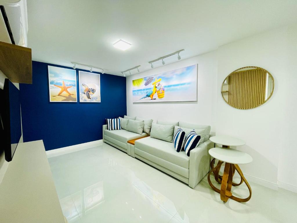 a living room with a couch and a blue wall at Apartamento dos Sonhos na Praia dos Anjos in Arraial do Cabo
