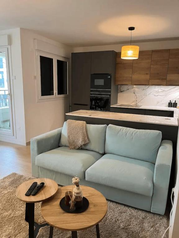 un salon avec un canapé bleu et une table dans l'établissement Modern apartment with terrace, à Saint-Ouen