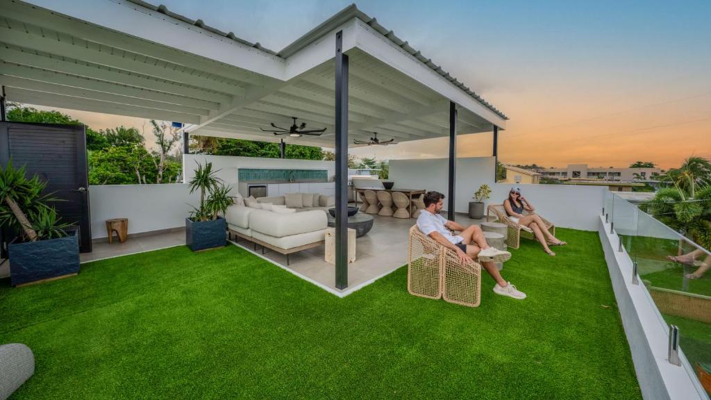 two people sitting in chairs on a patio with grass at Casa Loba Luxe Apartment with pool and ocean views in Rincon