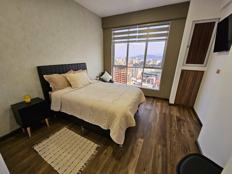 a bedroom with a large bed and a large window at Departamento en Cochabamba con hermosa vista in Calacala